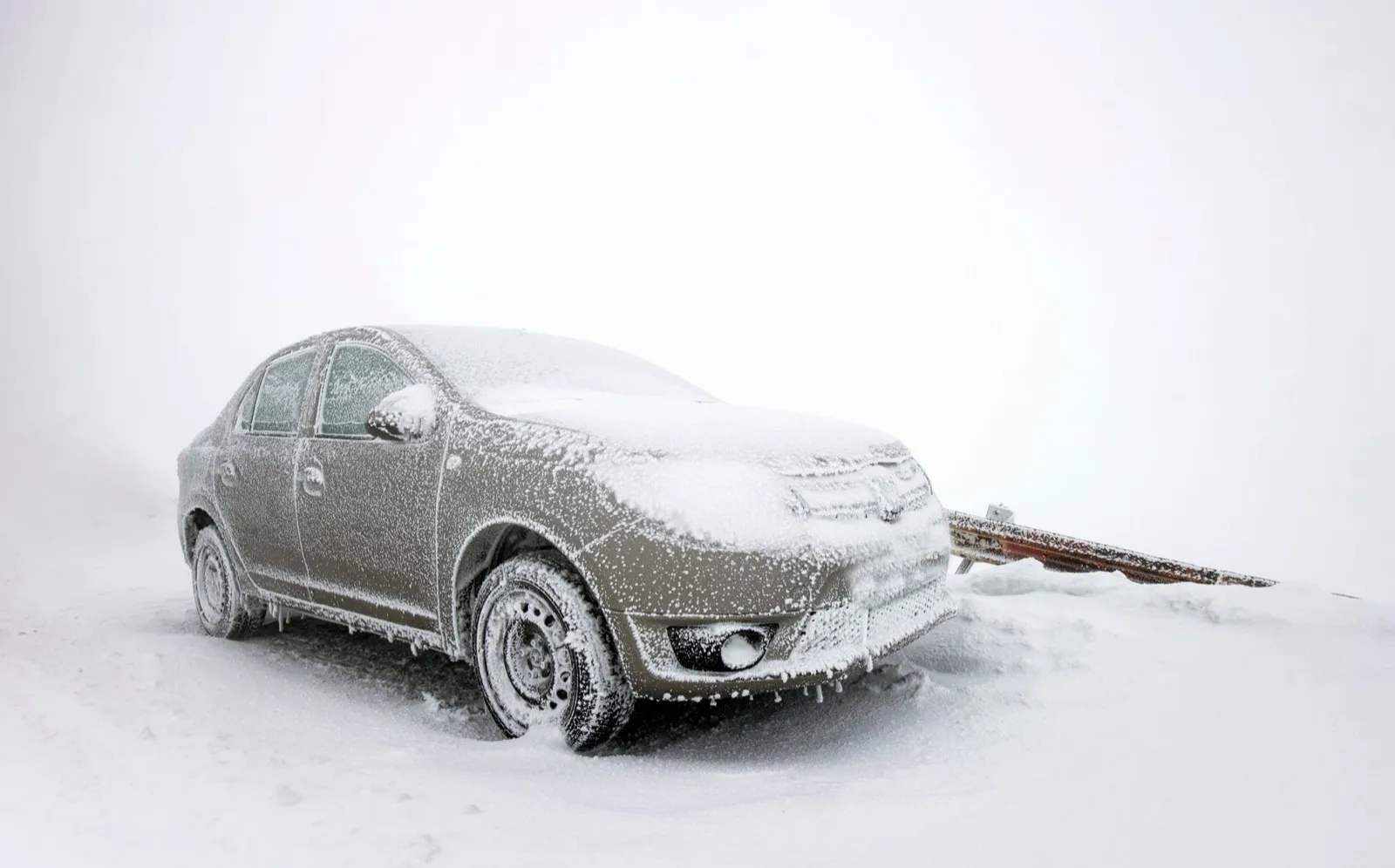 A sedan coated in ice and snow, parked on a frozen lot